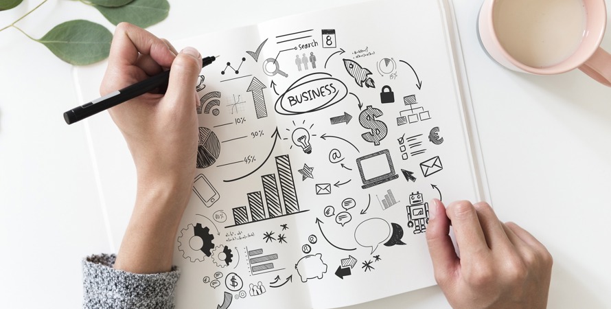 Två händer med en penna i hand som ritar på en affärsplan. 