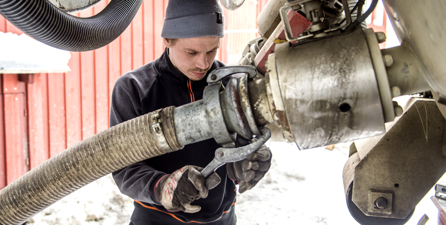 Man som jobbar med att fästa slamtömningsslangen på lastbilen.