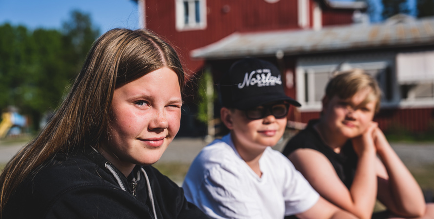 Tre barn sitter utanför Blattnicksele skola.